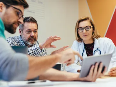 Gespräch zwischen Ärztin und drei Patienten an einem Tisch
