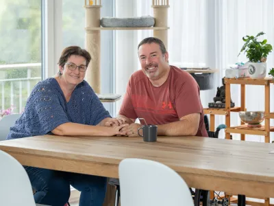 Pierre-Alain Tercier und seine Partnerin Mireille Schafer sitzen am Esstisch und halten sich an den Händen.