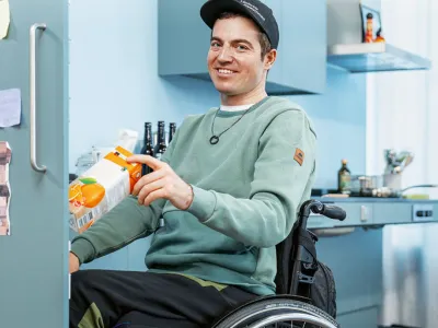 Mann im Rollstuhl am Kühlschrank
