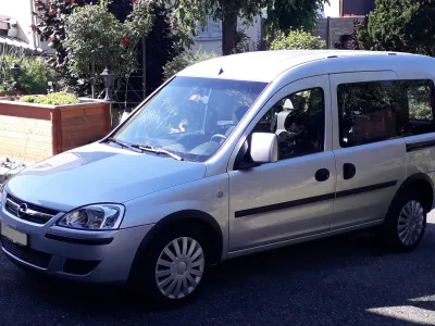 Silberner Opel Combo Kleinbus parkt am Straßenrand vor Häusern.