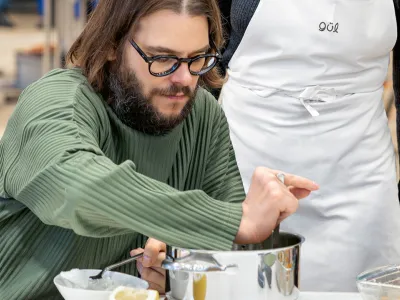 Rollstuhlfahrer hantiert mit einer Pfanne beim Kochen.