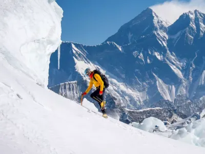 A mountaineer hiking through deep snow in a snowy, mountainous landscape.