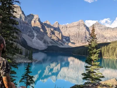A serene alpine lake surrounded by snow-capped mountains and dense evergreen forests.