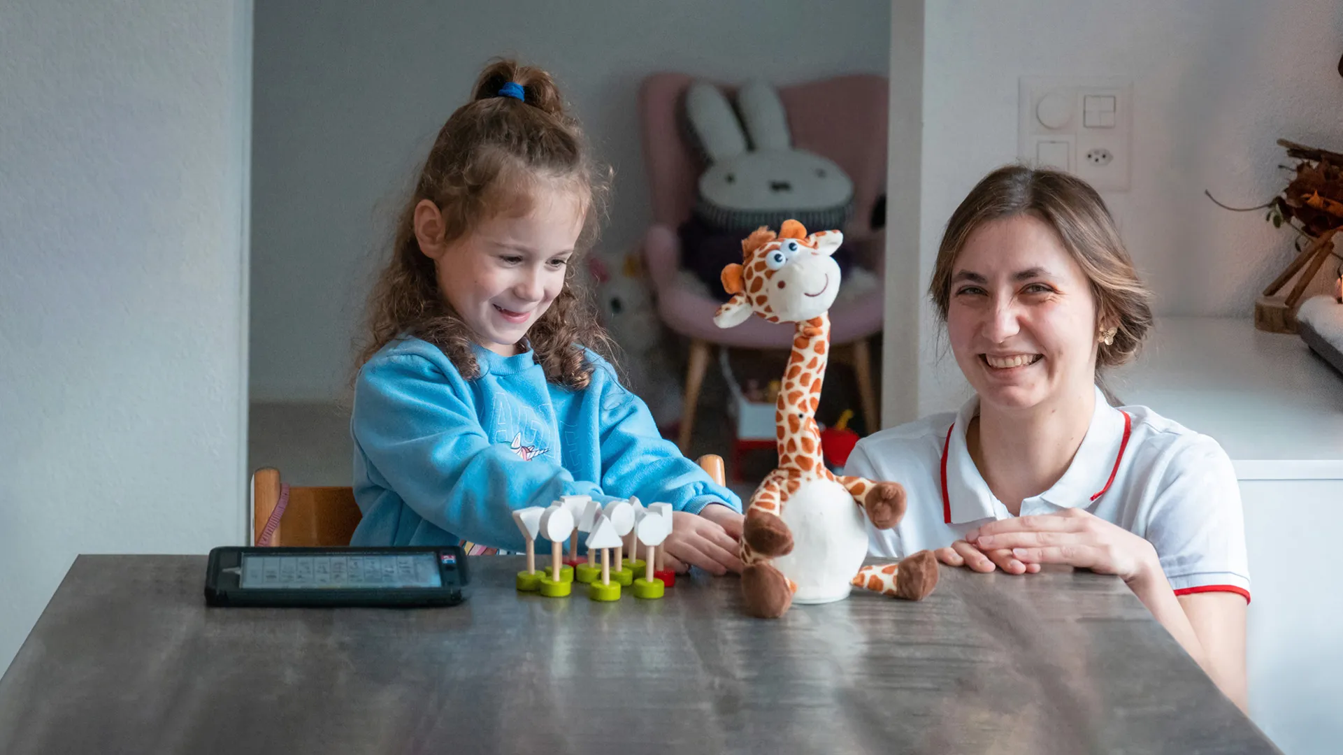 Mia Schuler spielt mit sprechneder Giraffe zusammen mit Beraterin Hannah