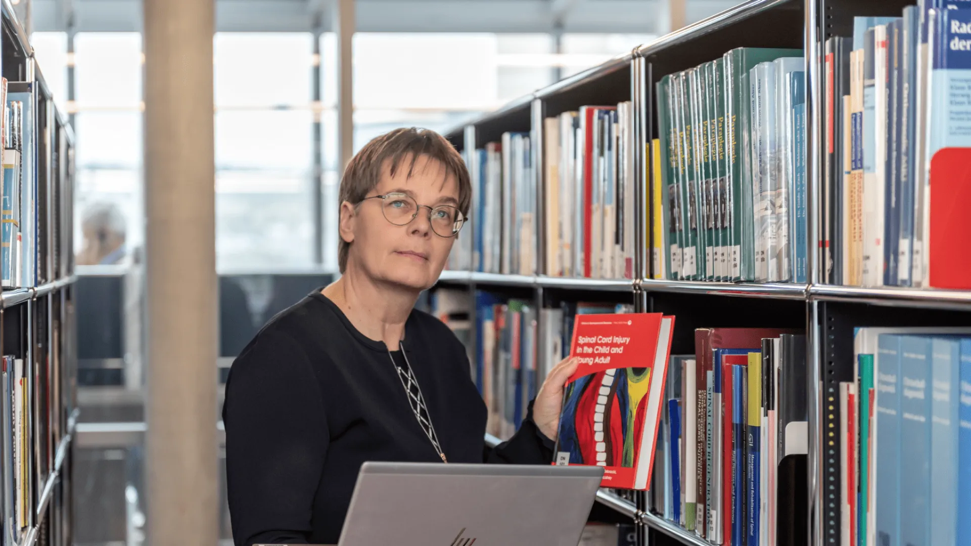 Daniela Denzer nimmt ein Buch aus dem Büchergestell.