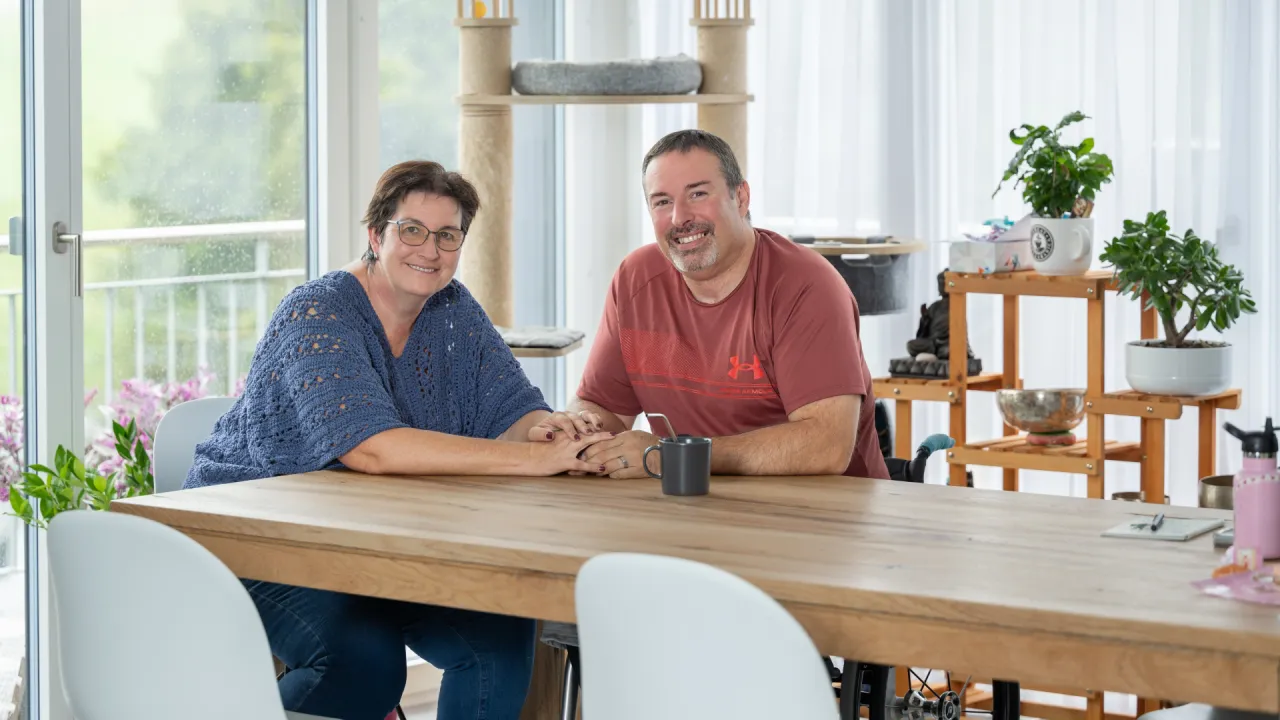 Pierre-Alain Tercier und seine Partnerin Mireille Schafer sitzen am Esstisch und halten sich an den Händen.