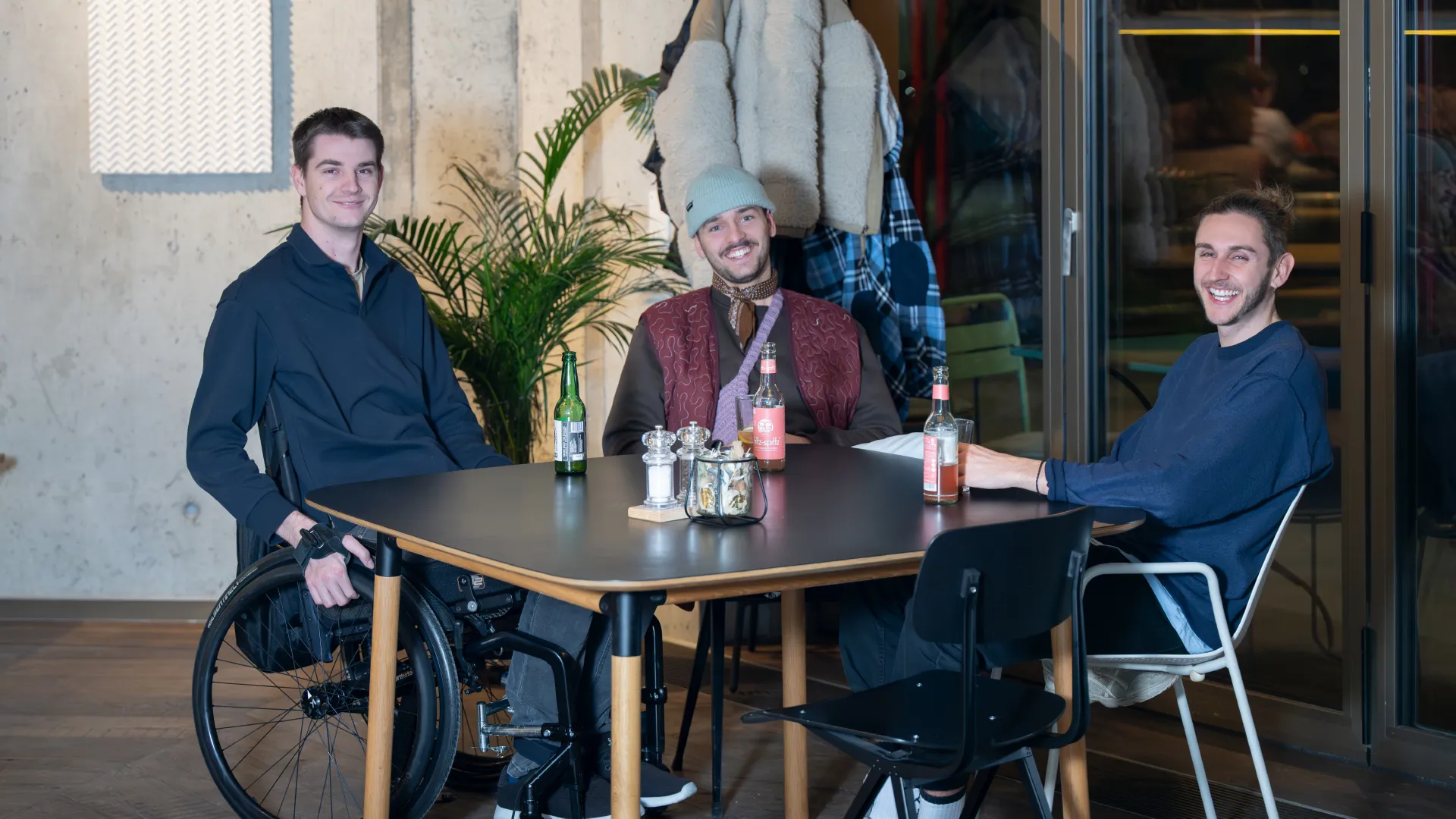 Drei Freunde sitzen am Tisch.