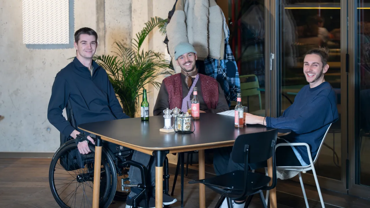 Drei Freunde sitzen am Tisch.