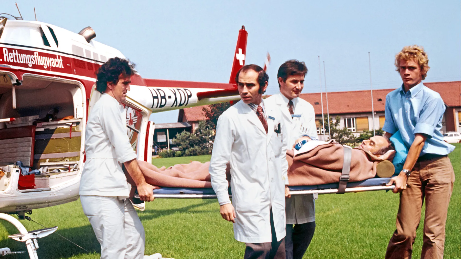 Guido A. Zäch und zwei weitere Männer transportieren einen Patienten aus dem Helikopter. Historisches Bild aus Basel.
