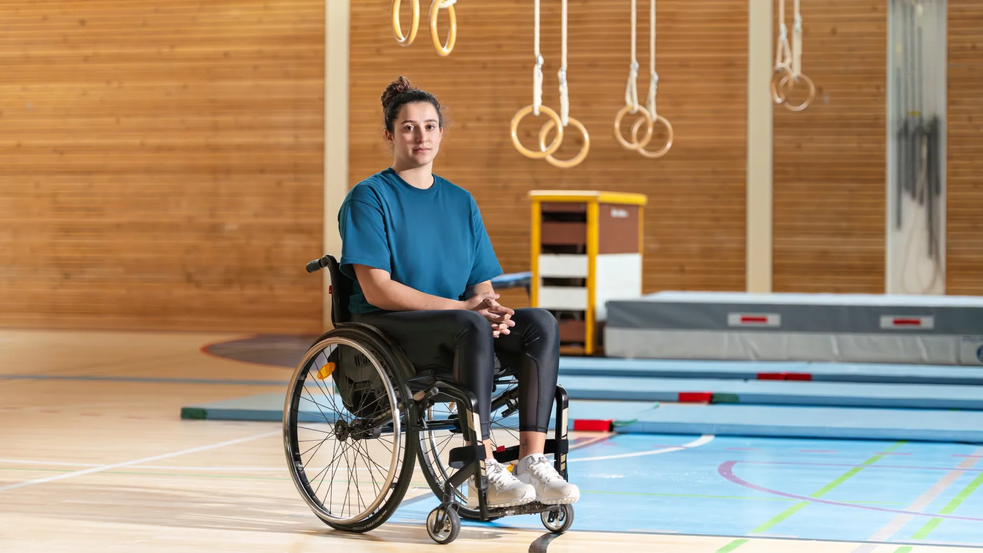 Giulia Damiano est assise dans son fauteuil roulant dans une salle de gymnastique.