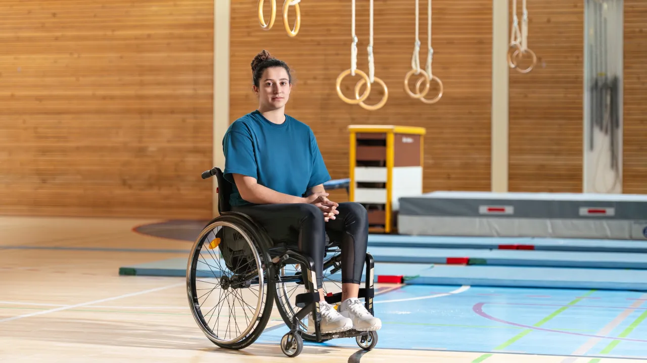 Giulia Damiano est assise dans son fauteuil roulant dans une salle de gymnastique.