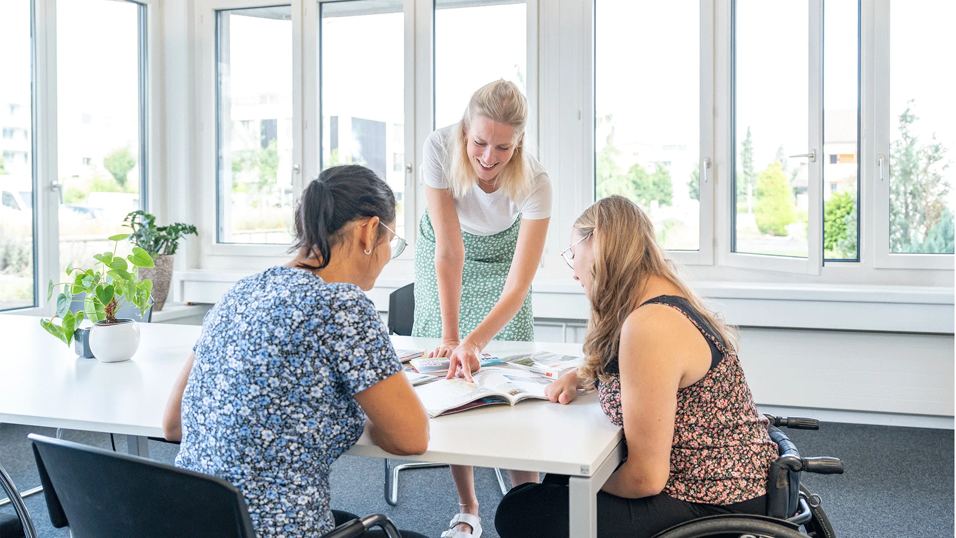 Drei Frauen sitzen um einen Tisch und besprechen etwas.