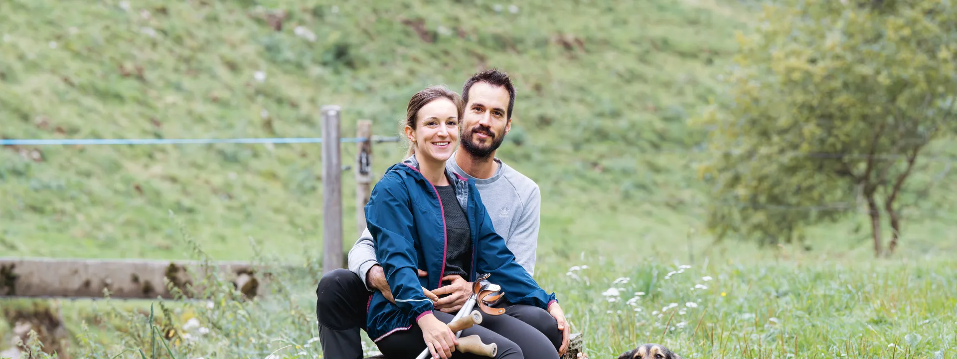 Andrea Treier und ihr Partner Andreas Signer sitzen auf einer Wiese.