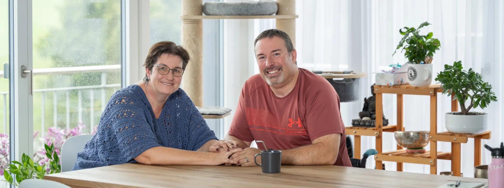 Pierre-Alain Tercier und seine Partnerin Mireille Schafer sitzen am Esstisch und halten sich an den Händen.