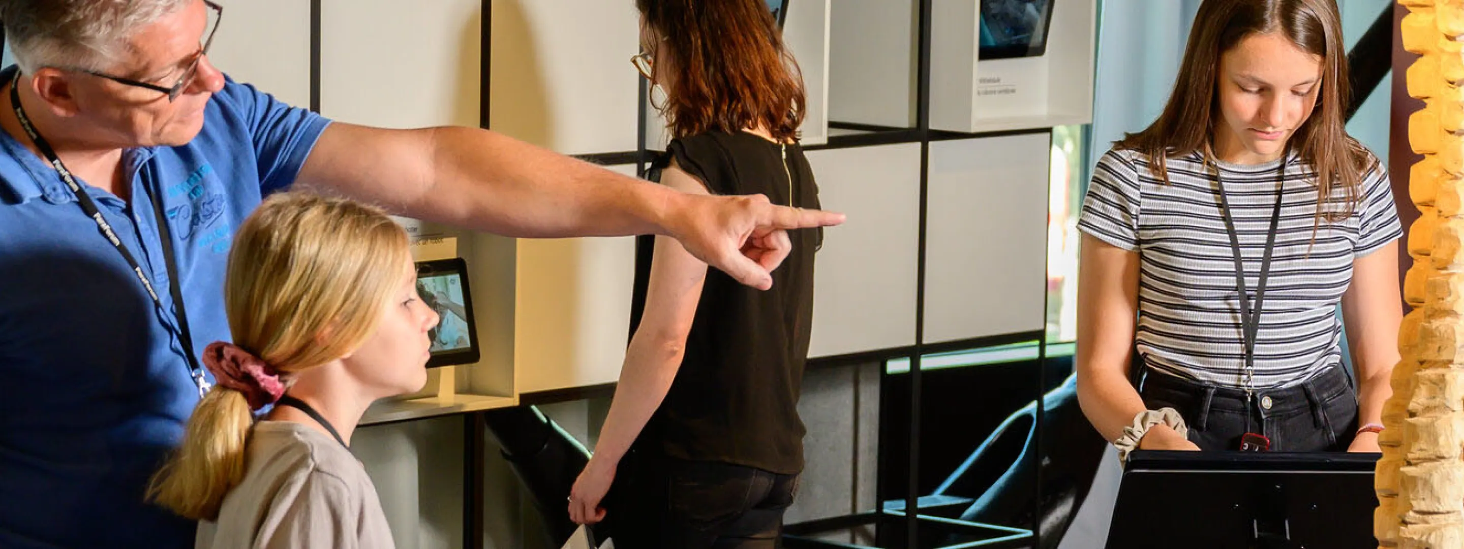 Eine Familie ist im Besuchszentrum ParaForum und schaut sich die Ausstellung an. Der Vater zeigt auf eine Wirbelsäule und seine Tochter hört ihm zu.