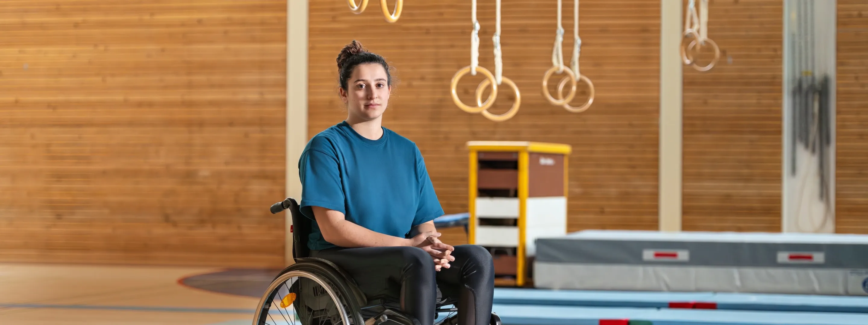 Giulia Damiano est assise dans son fauteuil roulant dans une salle de gymnastique.