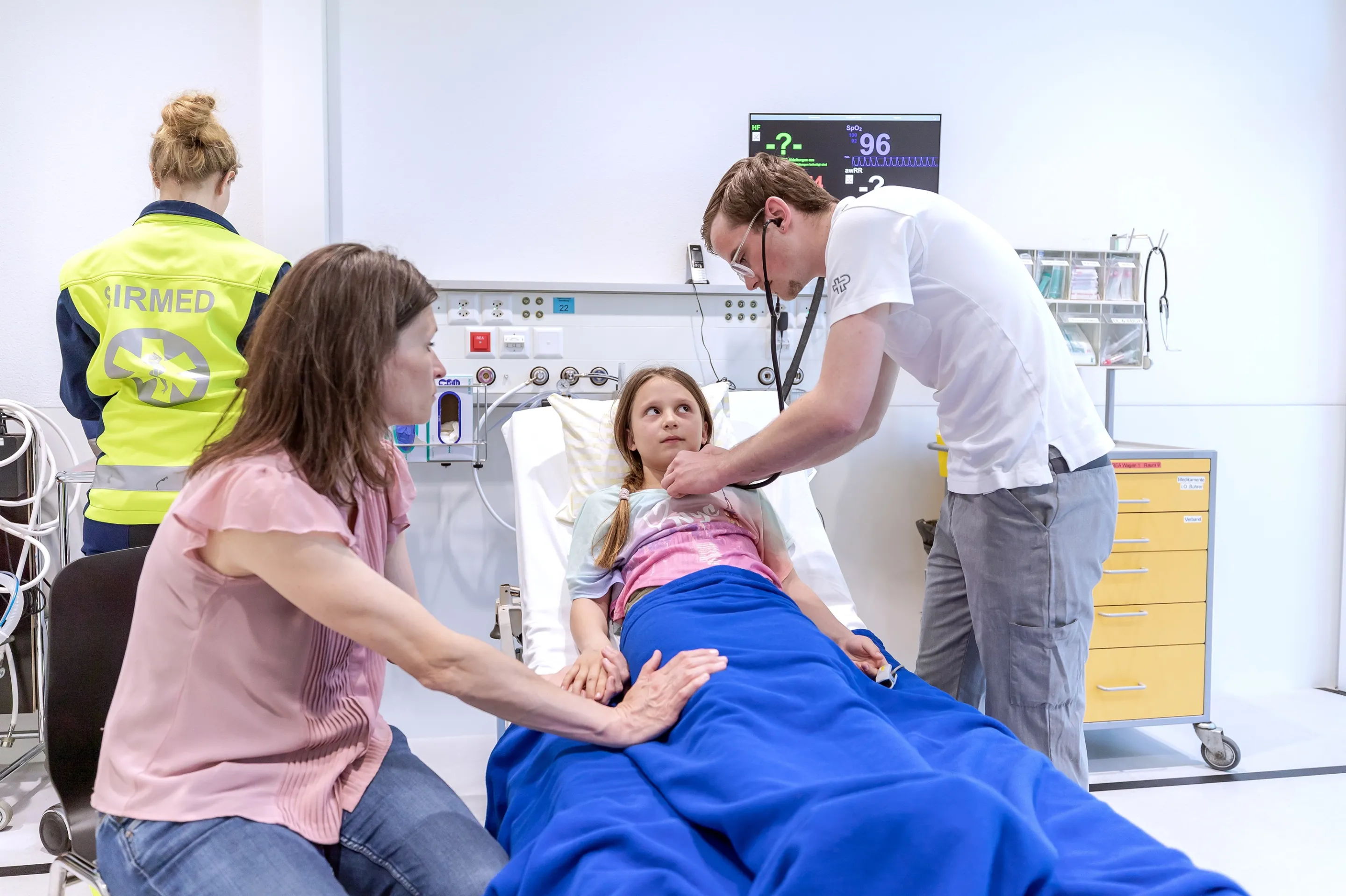 Medical professionals examining a patient on a hospital bed