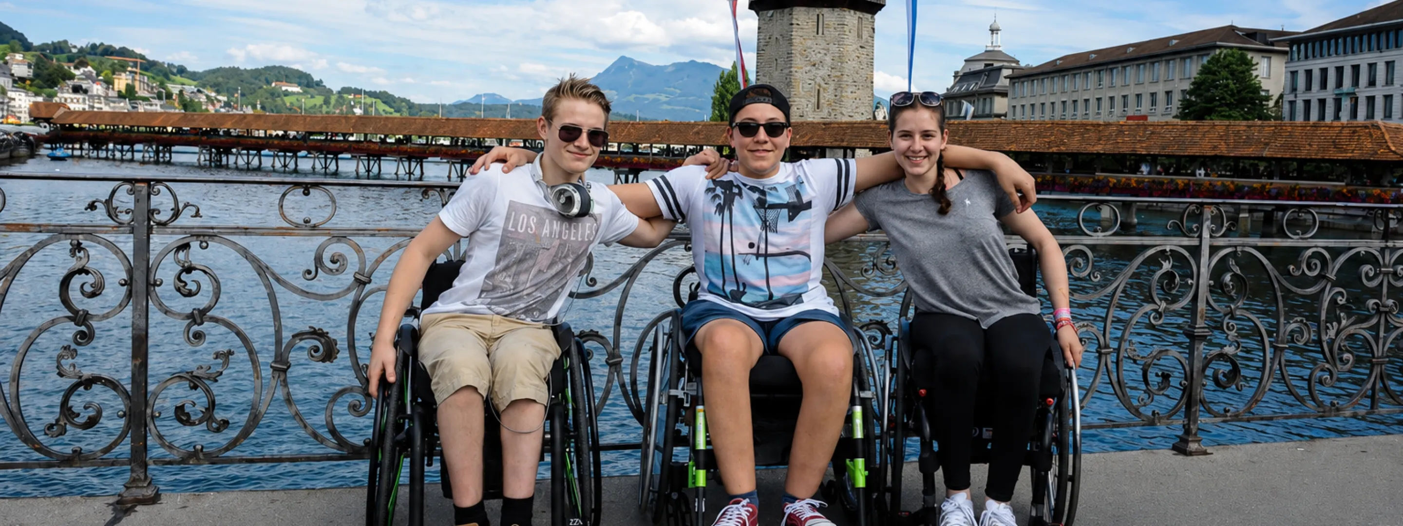 Four people in wheelchairs pose together on a bridge in Lucerne, Switzerland.