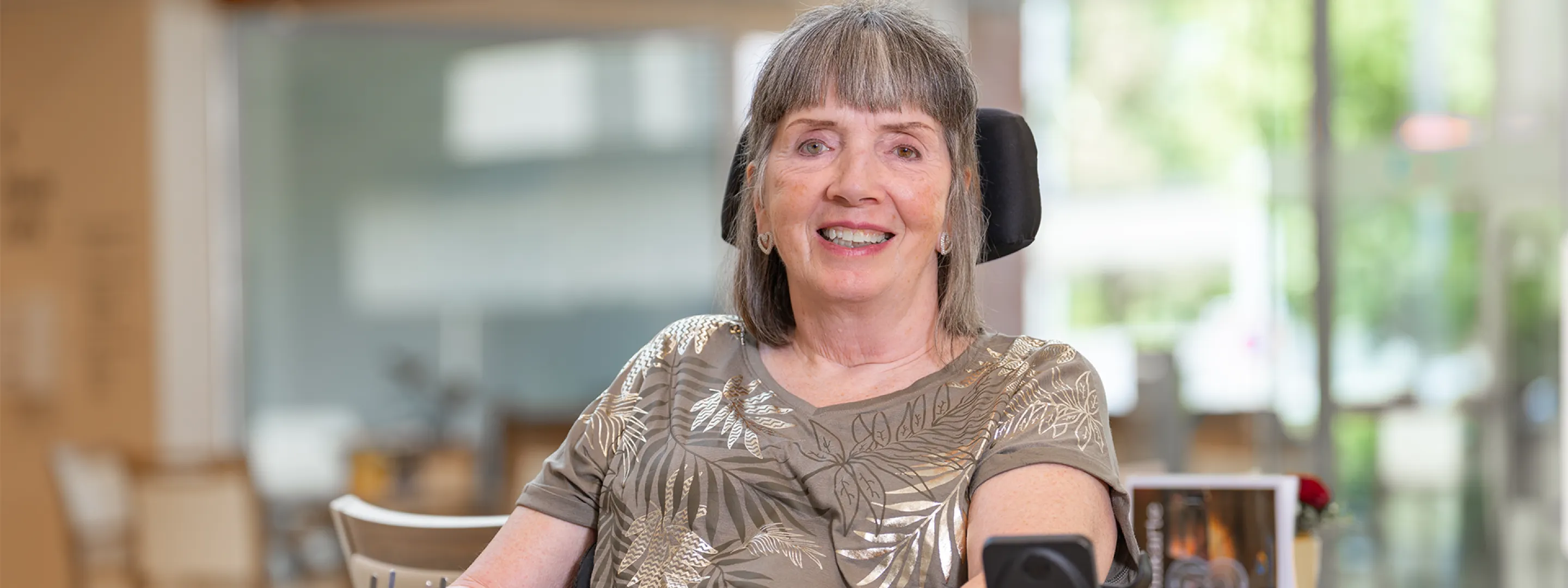 A smiling woman in a wheelchair in a room with a wooden interior.