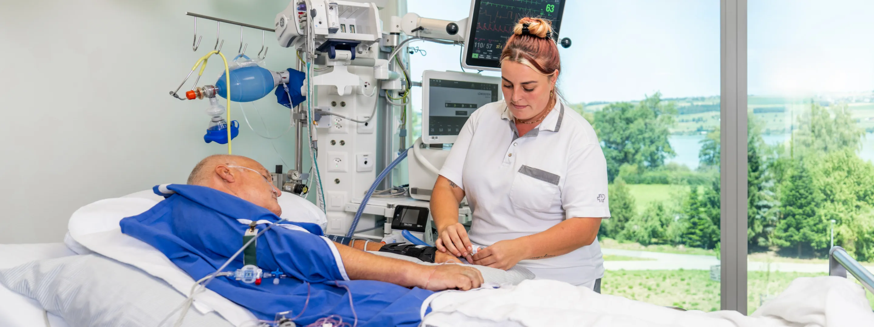 A nurse in hospital scrubs stands next to a patient's bed.