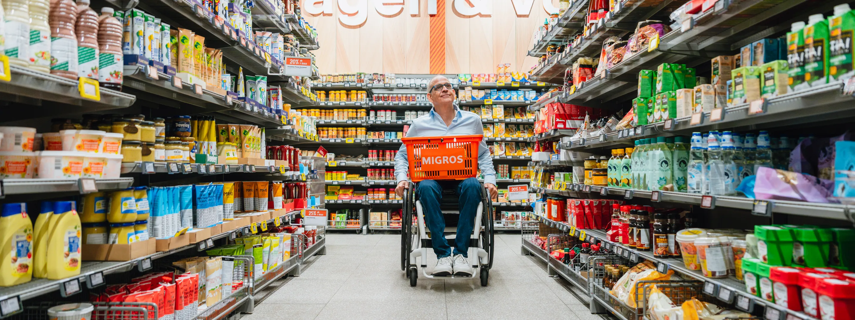Aisle of a grocery store with various shelved products and a shopping cart.