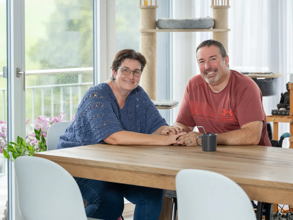 Pierre-Alain Tercier und seine Partnerin Mireille Schafer sitzen am Esstisch und halten sich an den Händen.