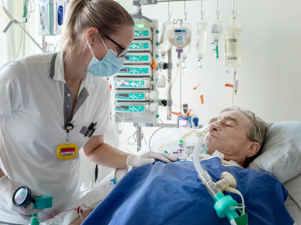 Ein Mann liegt in einem Spitalbett und wird beatmet.