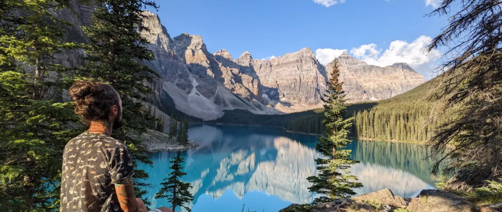 A serene alpine lake surrounded by snow-capped mountains and dense evergreen forests.