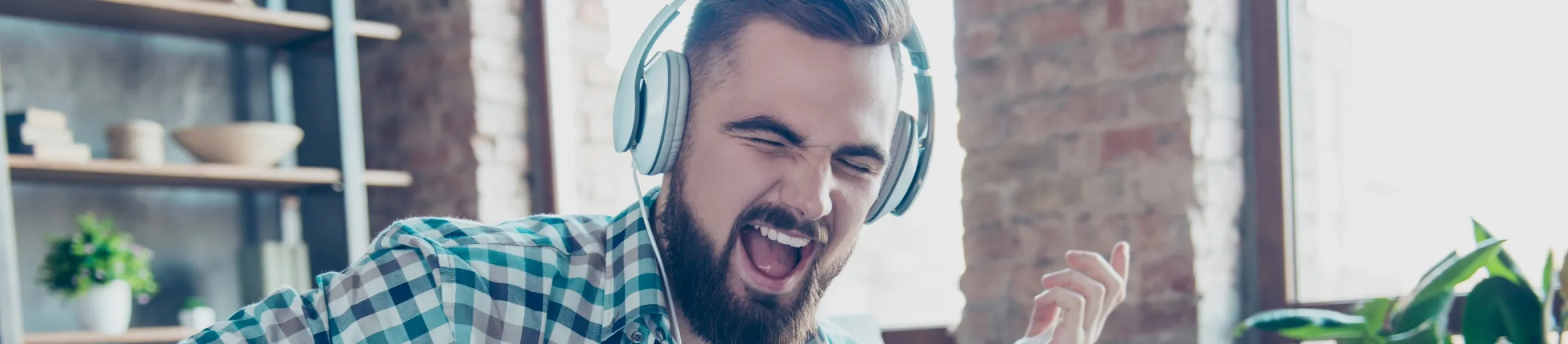 Un homme porte un casque, joue de la guitare imaginaire et chante.