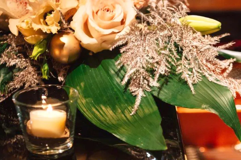 Festlicher Blumenstrauss mit brennender Kerze auf einem Konzertflügel.
