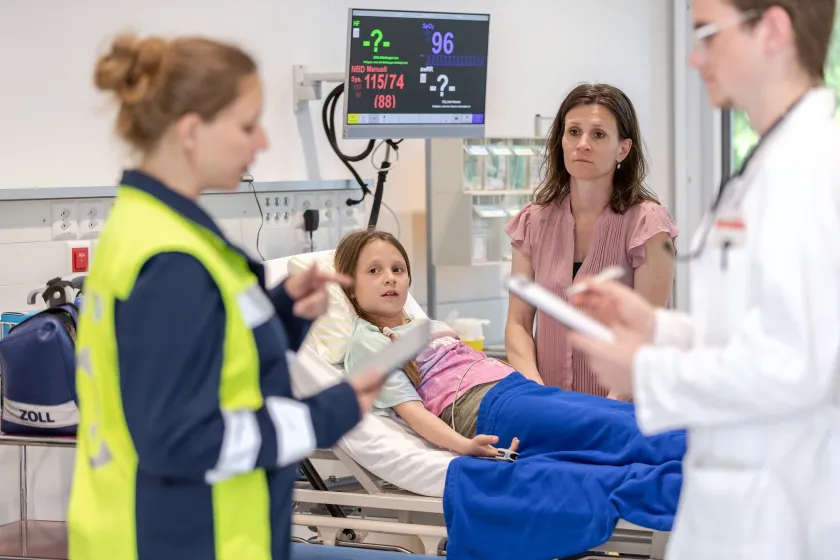 Medical team treating patient on hospital bed with vital signs monitor