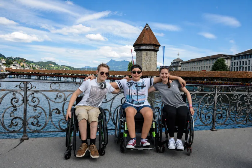 Four people in wheelchairs pose together on a bridge in Lucerne, Switzerland.