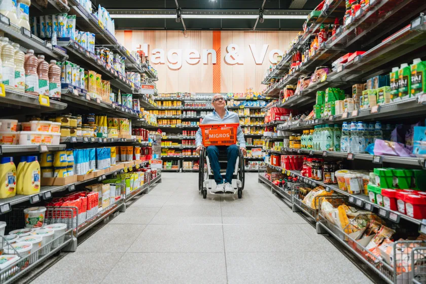 Aisle of a grocery store with various shelved products and a shopping cart.