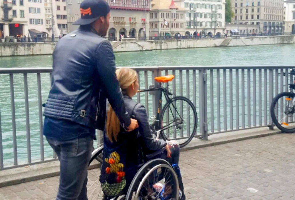Rollstuhlfahrerin lässt sich durch die Stadt stossen