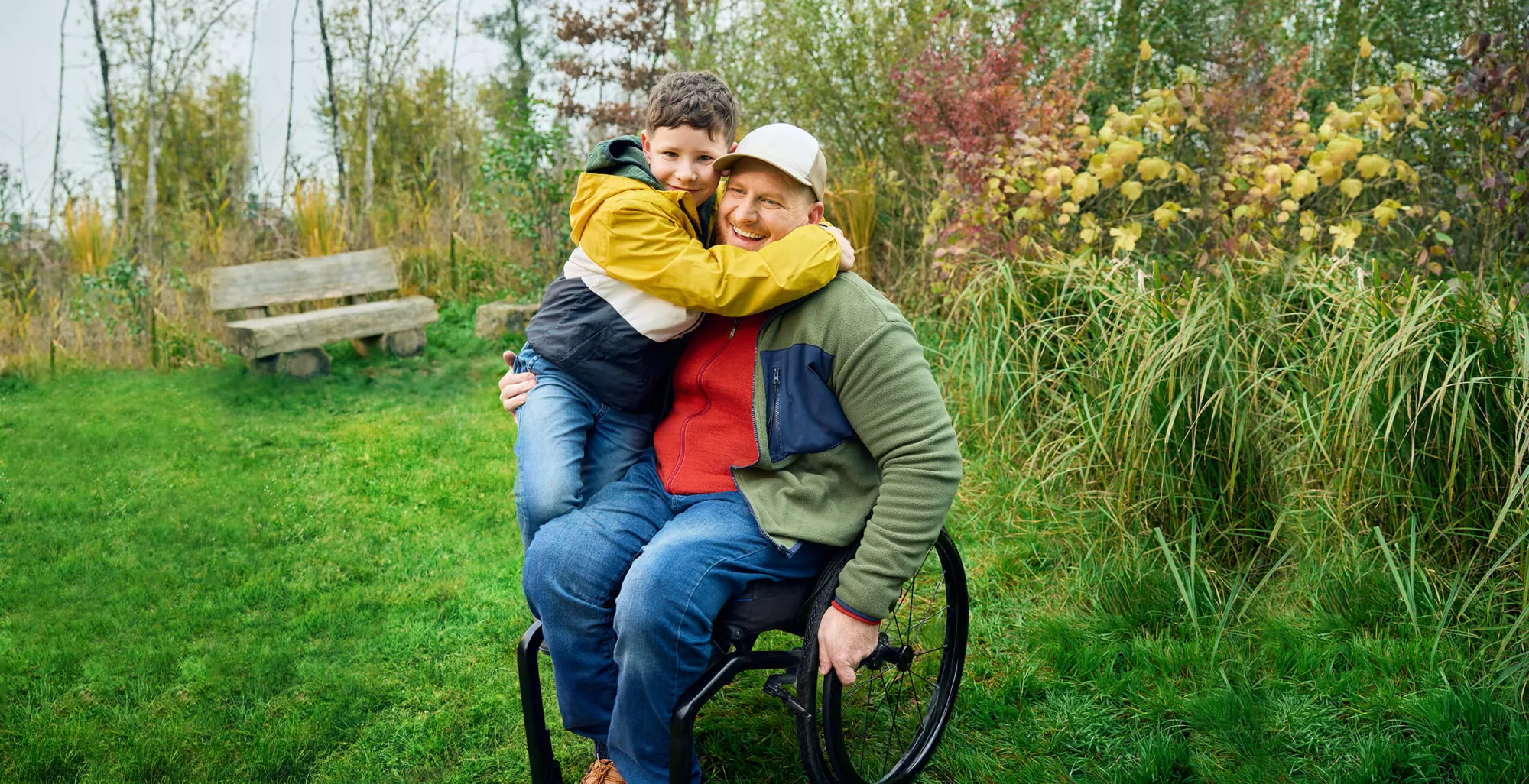 Heiri siede nella sua carrozzina su un prato e suo figlio gli sale in grembo e abbraccia forte forte suo papà. Tutti e due sorridono.