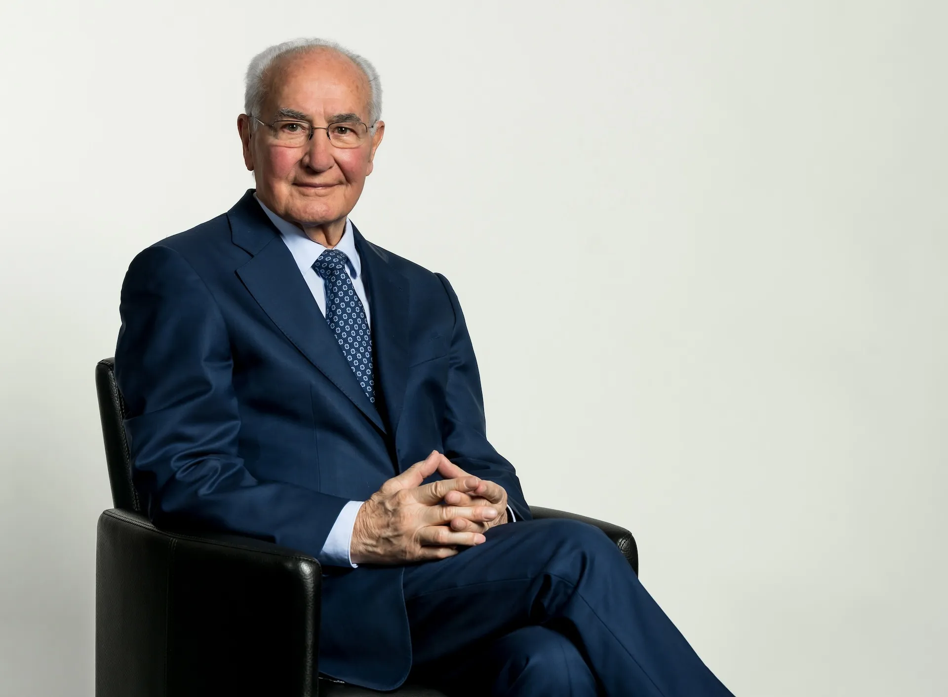 Guido A. Zäch in dunklem Anzug in einem Sessel.