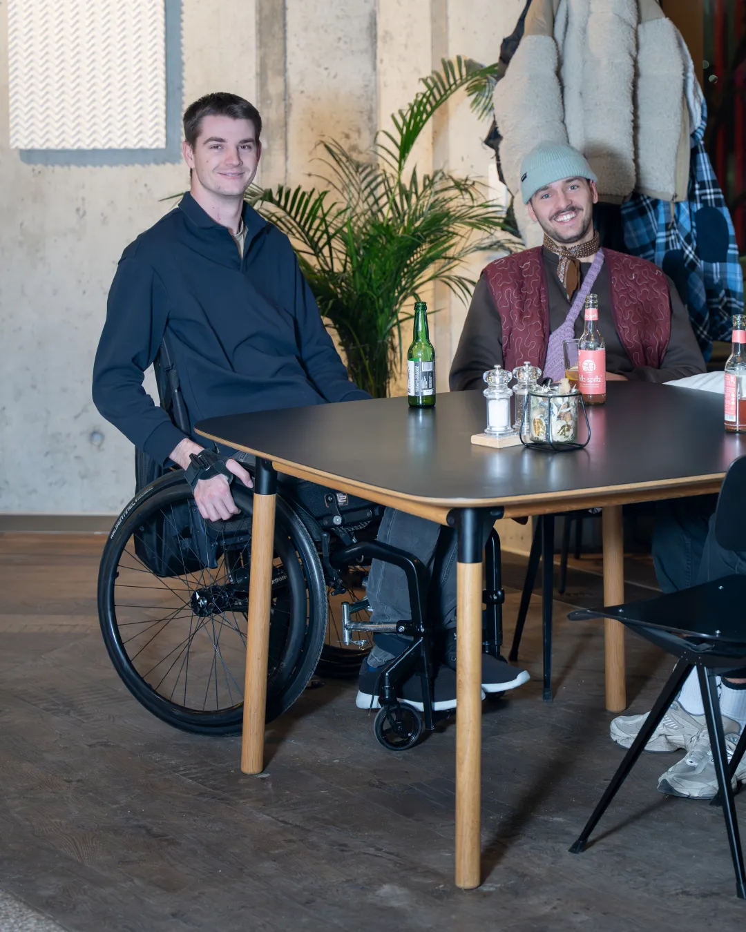 Nico Schmid sitzt mit seinen Freunden am Tisch und sie lachen in die Kamera