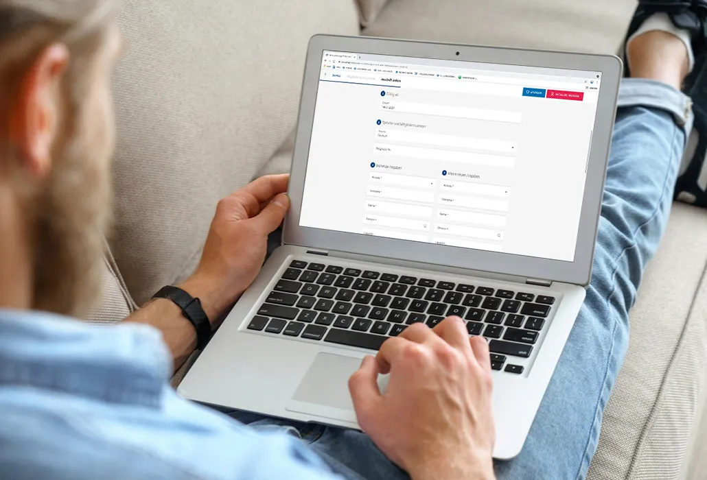 Ein Mann sitzt auf dem Sofa mit dem Laptop auf den Beinen. Auf dem Bildschirm sieht man das Formular für die Adressänderung bei einer Mitgliedschaft bei der Gönner-Vereinigung der Schweizer Paraplegiker-Stiftung.