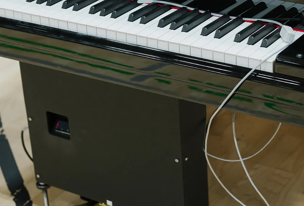 Das Silikonröhrchen montiert die Pianistin, der Pianist in der Kleidung. Es führt zur Box, die das Pedal bedient.