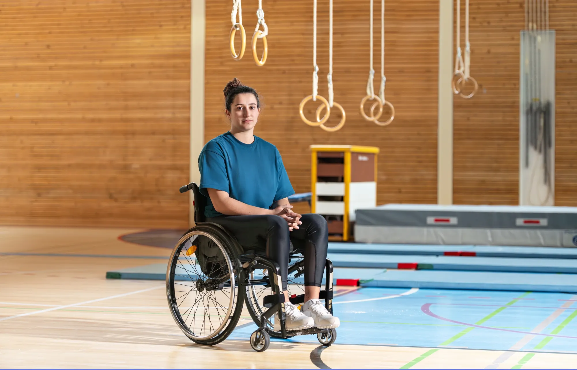 Giulia Damiano est assise dans son fauteuil roulant dans une salle de gymnastique.