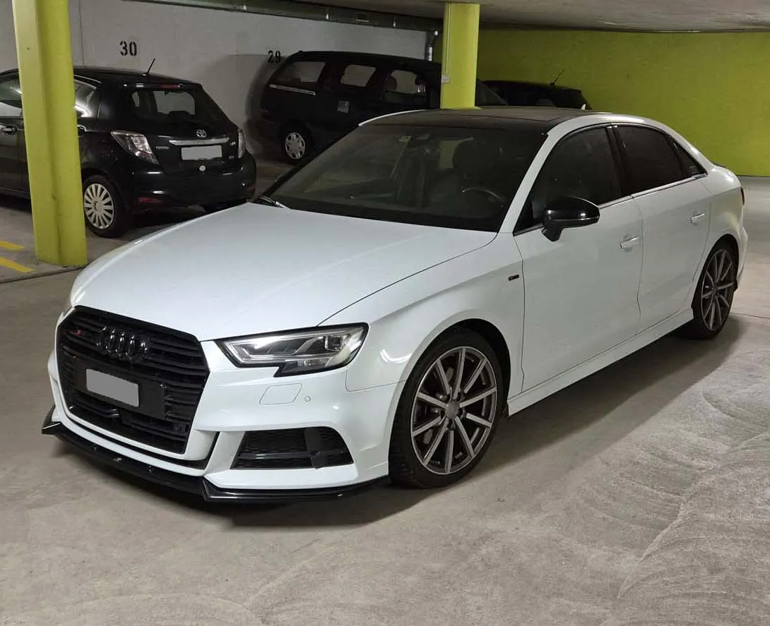 Weißer Audi A3 Limousine in einer Tiefgarage mit grünen Wänden.