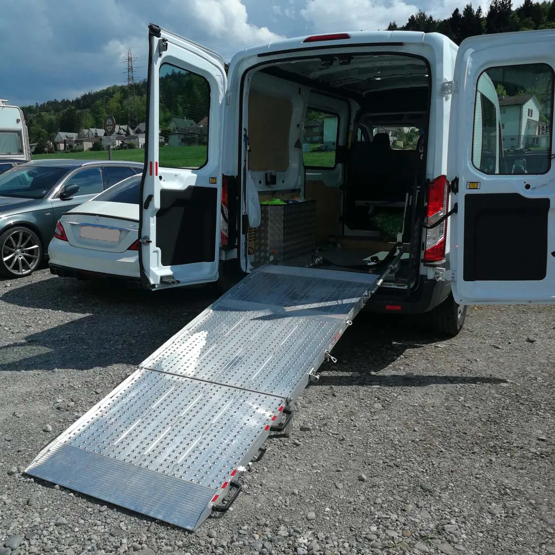 Behindertengerechter Transporter mit ausgefahrener Rampe auf einem Parkplatz.