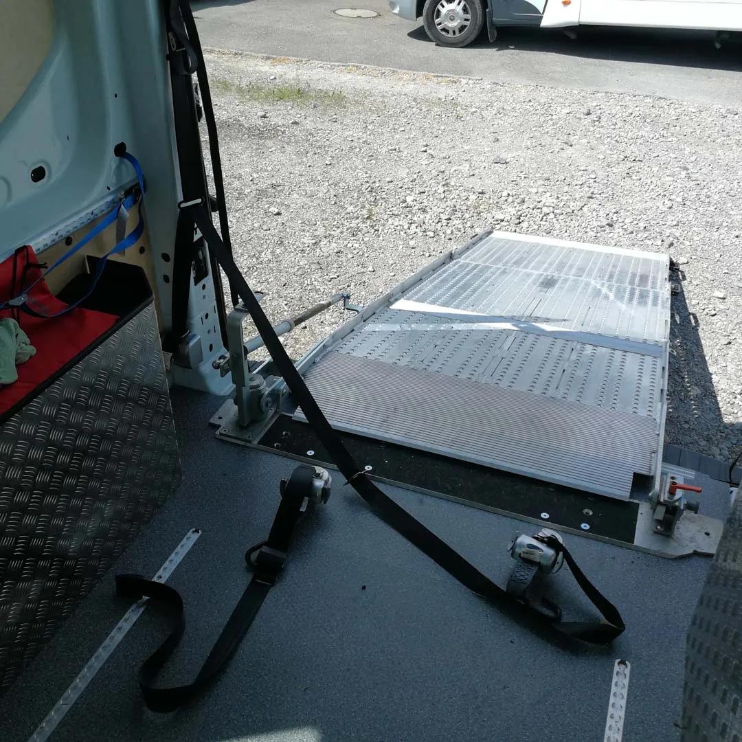 Rollstuhllift an der Rückseite eines Fahrzeugs, bereit zum Einsatz.