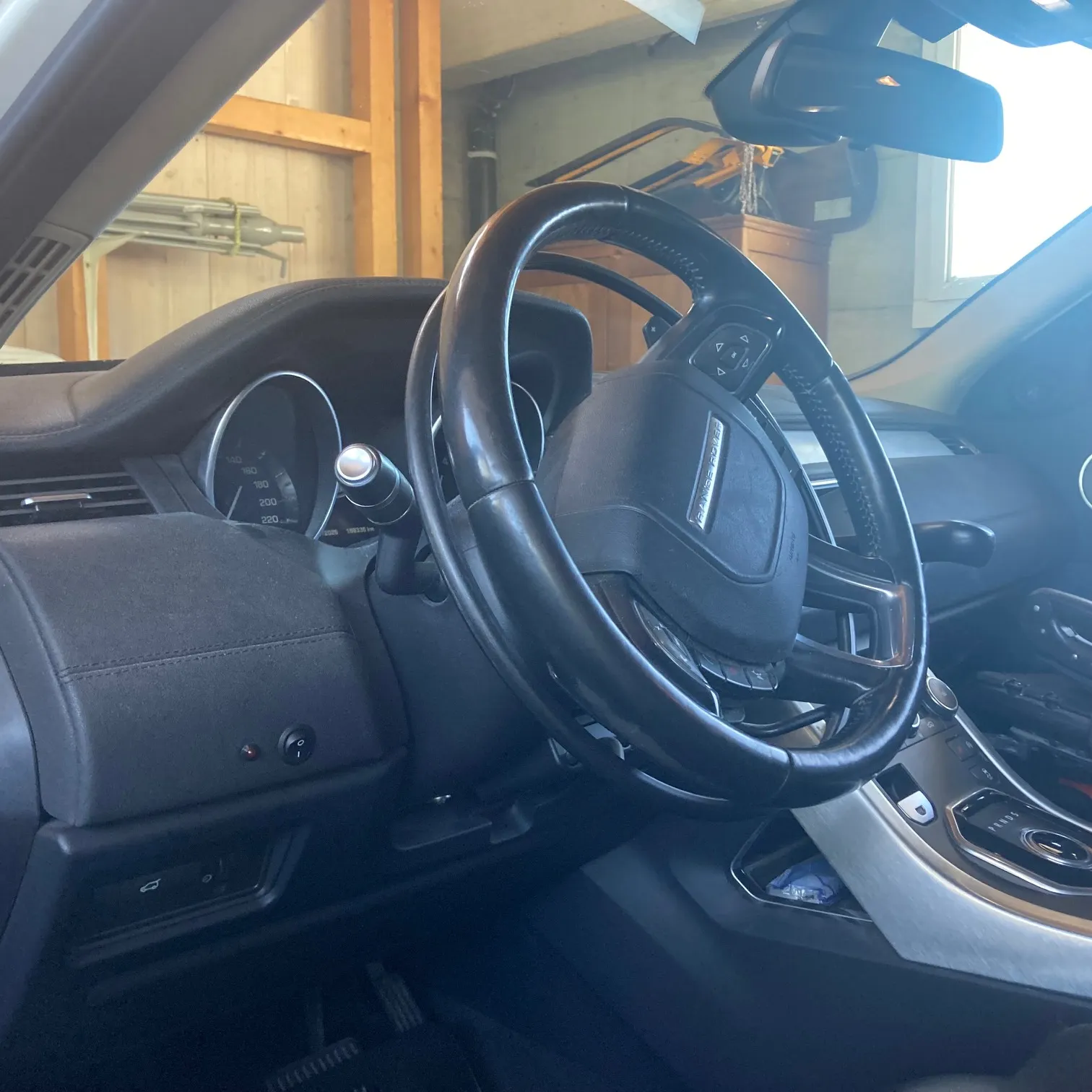 Innenraum eines Autos mit Lenkrad und Armaturenbrett, durch die Windschutzscheibe sichtbar.