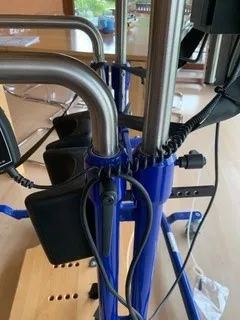 occasion-stehhilfe-schmied-05.jpg Blaues Spiralkabel verbindet Rollstuhl mit Steuereinheit im Krankenhaus.