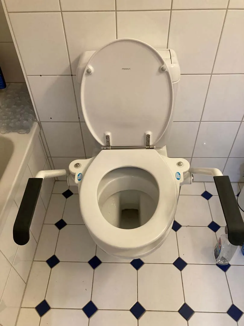 occasion-toilettensitzerhoehung-th-10-messerli-02.jpg Toilette mit weißem Sitz auf schwarz-weißem Fliesenboden in einem Badezimmer.