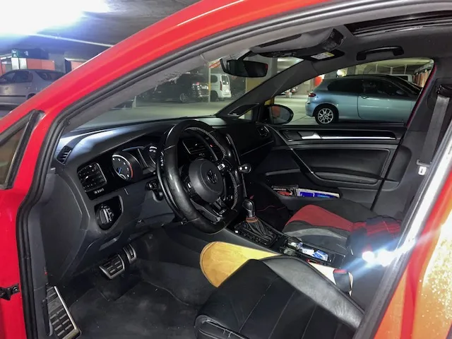 Rotes Auto mit geöffneter Tür, schwarzer Innenraum und Lenkrad sichtbar.