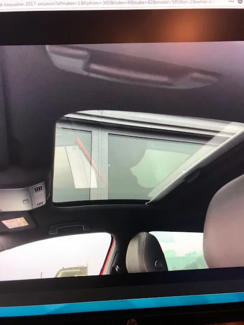 Innenansicht eines Fahrzeugs mit Seitenfenster und Dachfenster, dunkle Innenausstattung.