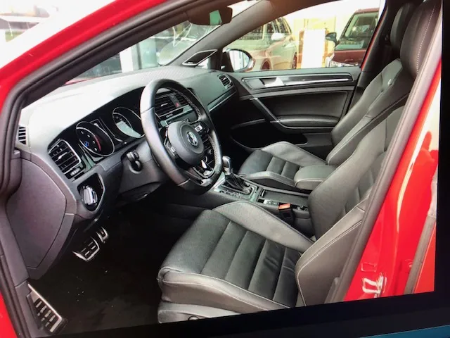 Innenraum eines roten Autos mit schwarzen Ledersitzen und Lenkrad.