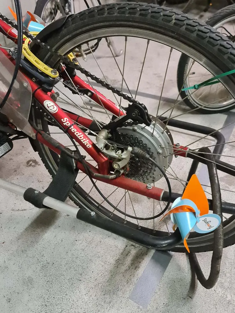 occasion-speedbike-nguyen-05.jpg Rotes Mountainbike mit schwarzem Rahmen und dicken Reifen, auf grauem Boden geparkt.